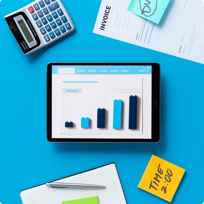 Xero invoicing software on an iPad surrounded by a calculator, invoice, Post-it notes, and notepad.