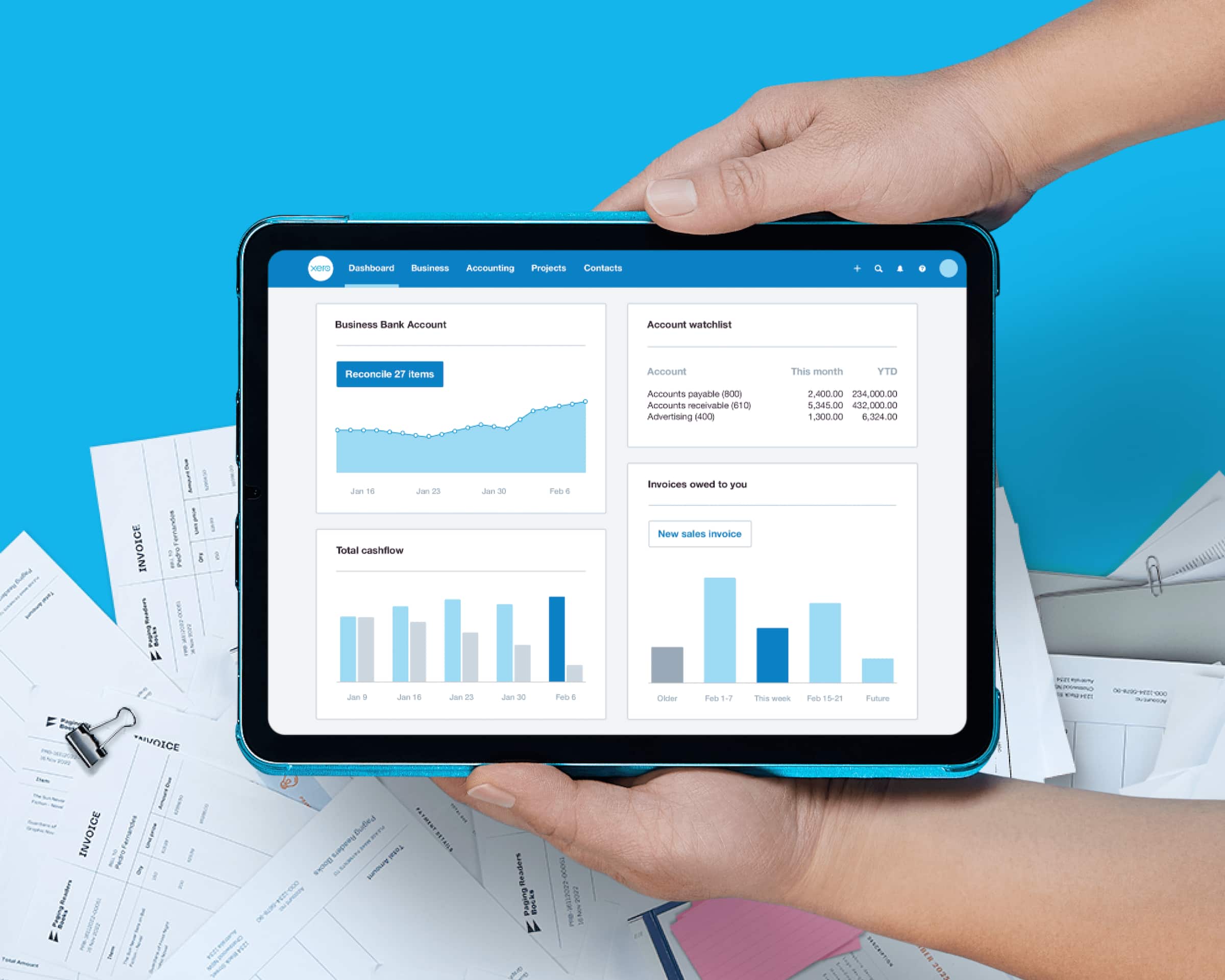 The Xero dashboard open on an iPad and held above scattered paper documents.