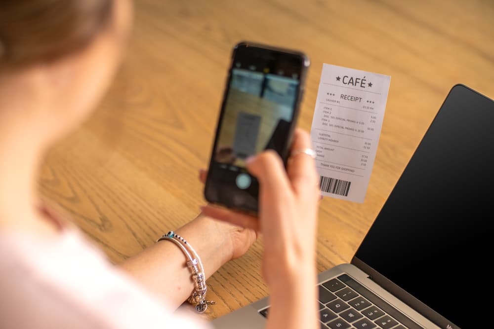 A small business owner photographs a receipt with their phone using Xero's expense management software.